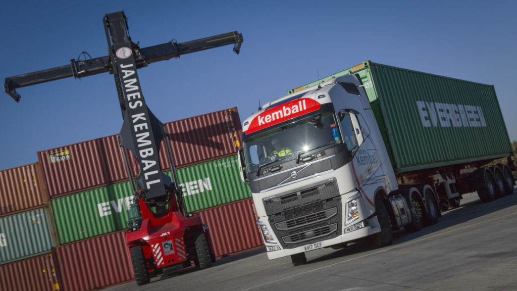 Heavy machinery being used to lift heavy shipping container and truck